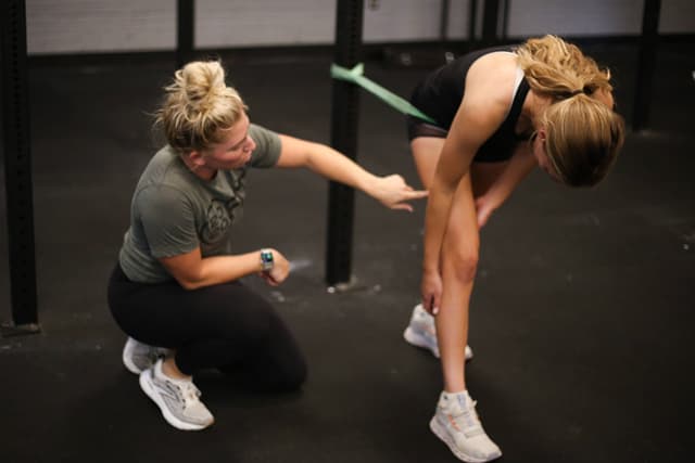 Coach guiding a member through a banded exercise